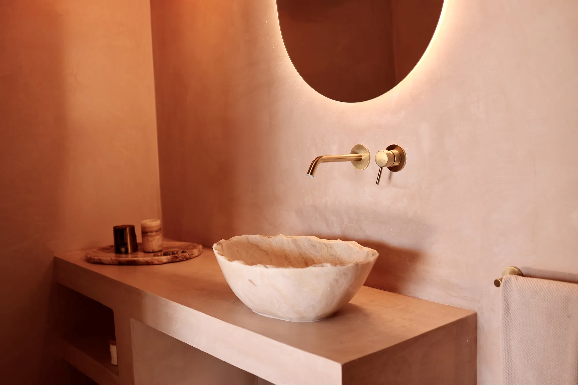 Eclipse bathroom: carved onyx basin glowing against the plaster wall